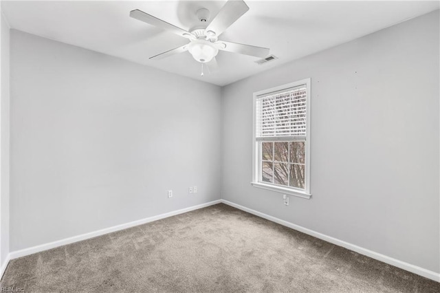 carpeted spare room with visible vents, baseboards, and ceiling fan