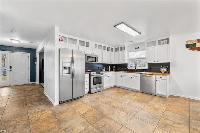 kitchen featuring a sink, tasteful backsplash, stainless steel appliances, white cabinets, and baseboards