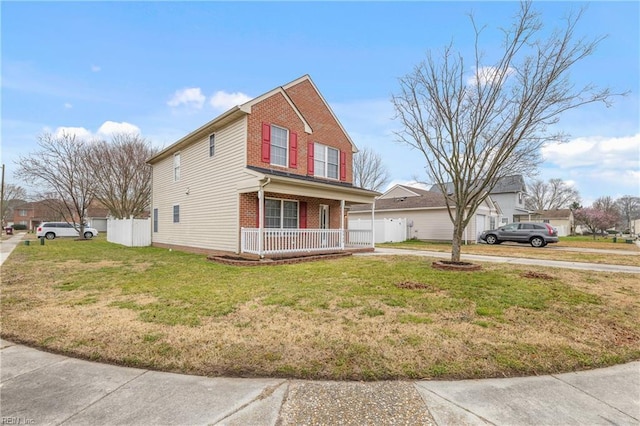 traditional home featuring brick siding, covered porch, a front yard, and fence