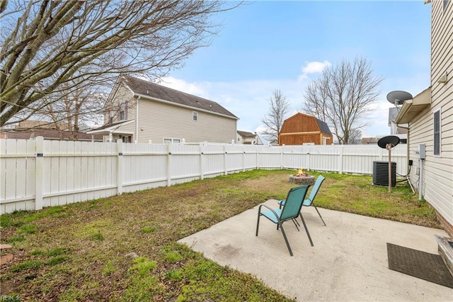 view of yard featuring a fire pit, central AC unit, a fenced backyard, and a patio area