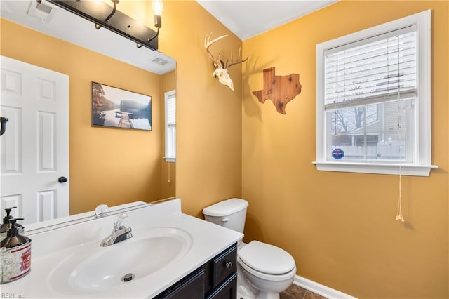 bathroom with vanity, toilet, baseboards, and visible vents