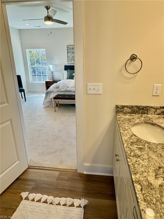 bathroom featuring vanity, wood finished floors, baseboards, ceiling fan, and connected bathroom