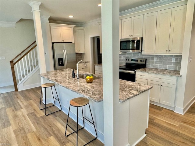 kitchen featuring a sink, stainless steel appliances, light wood-style floors, and crown molding