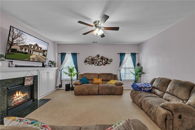 living area with a premium fireplace, a ceiling fan, baseboards, and light carpet