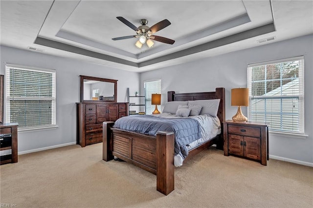 bedroom featuring visible vents, a raised ceiling, and baseboards