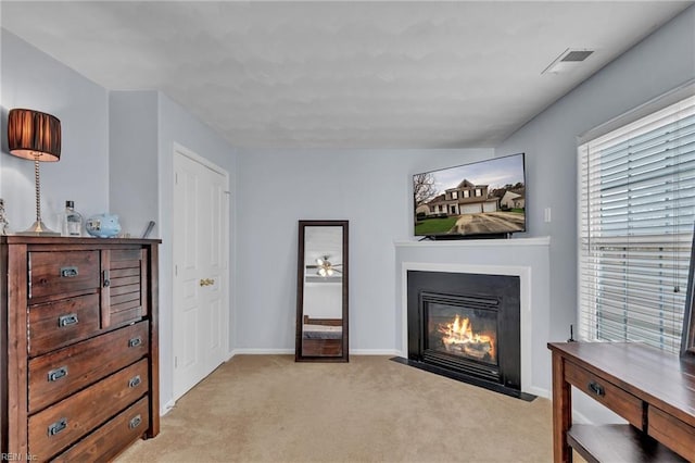 sitting room featuring visible vents, a fireplace with flush hearth, light colored carpet, and baseboards