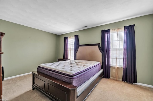 bedroom with visible vents, baseboards, and light carpet