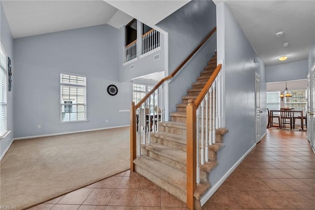 stairs with visible vents, baseboards, high vaulted ceiling, tile patterned flooring, and carpet flooring