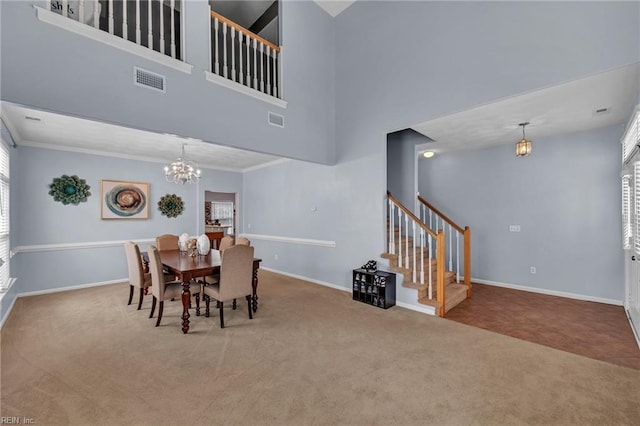 carpeted dining room featuring baseboards, visible vents, an inviting chandelier, ornamental molding, and stairs