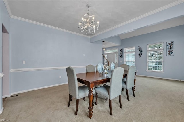 carpeted dining room featuring an inviting chandelier, baseboards, and ornamental molding