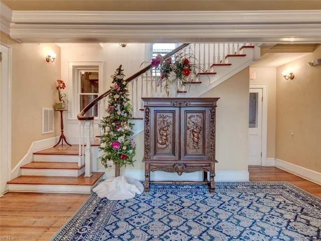 entrance foyer with stairway, baseboards, visible vents, and wood finished floors