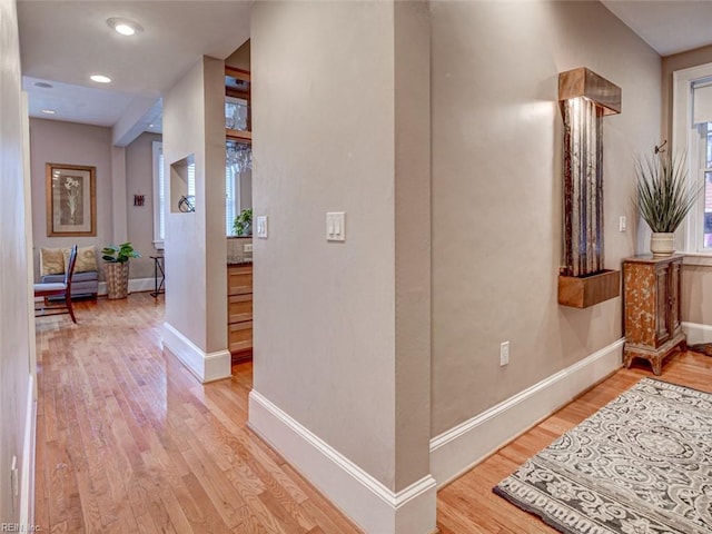 hallway featuring light wood-style flooring, recessed lighting, and baseboards