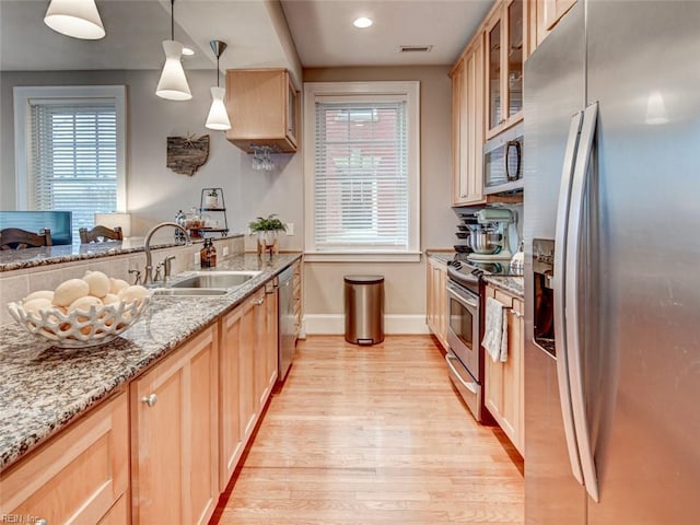 kitchen with visible vents, a sink, light wood-style floors, appliances with stainless steel finishes, and glass insert cabinets