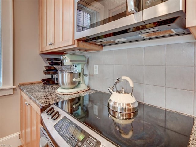 kitchen featuring stainless steel microwave, light stone countertops, and decorative backsplash