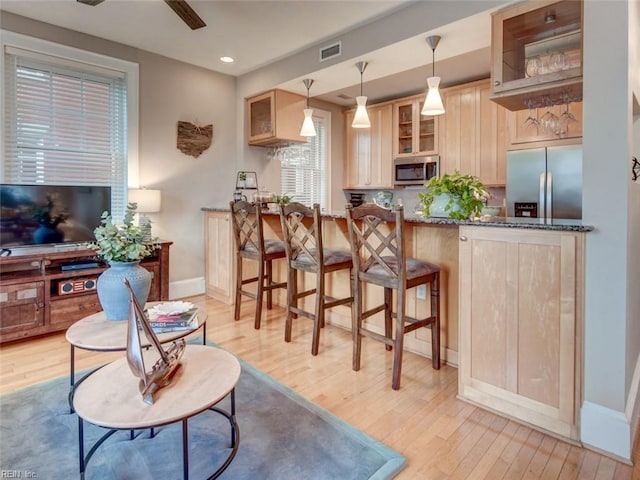 kitchen with glass insert cabinets, light brown cabinets, and stainless steel appliances