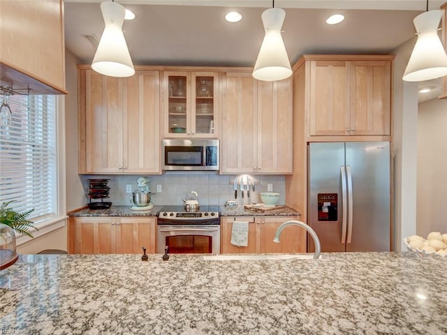 kitchen featuring light brown cabinetry, appliances with stainless steel finishes, tasteful backsplash, and light stone counters