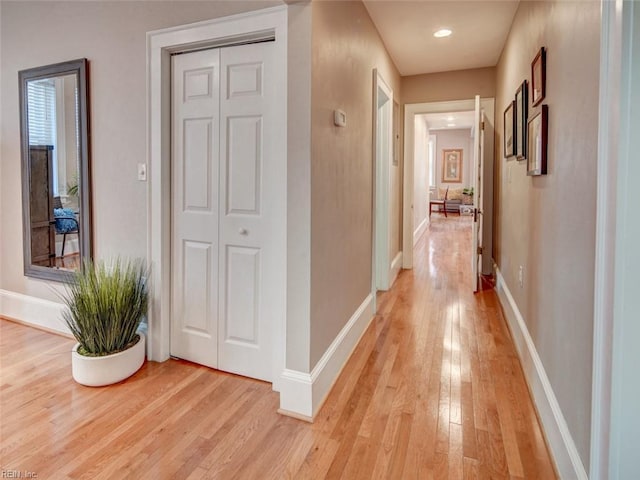 hallway with light wood finished floors and baseboards