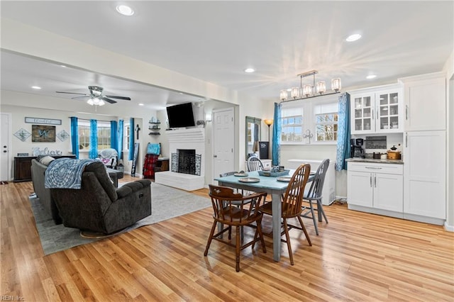 dining room featuring recessed lighting, ceiling fan, a fireplace, and light wood finished floors