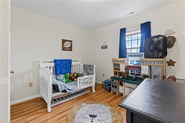 bedroom featuring visible vents, light wood-style flooring, and baseboards