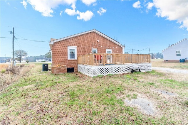 back of property featuring a yard, brick siding, central AC, and a wooden deck