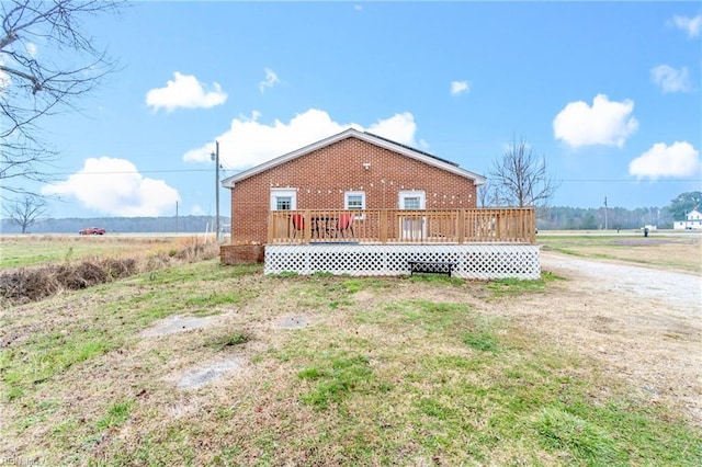 back of property with a deck and a lawn