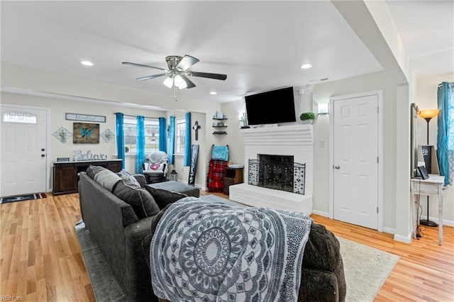 living area with baseboards, recessed lighting, light wood-style flooring, a fireplace, and a ceiling fan