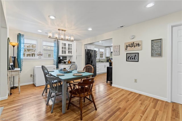 dining space featuring visible vents, plenty of natural light, light wood-type flooring, and an inviting chandelier