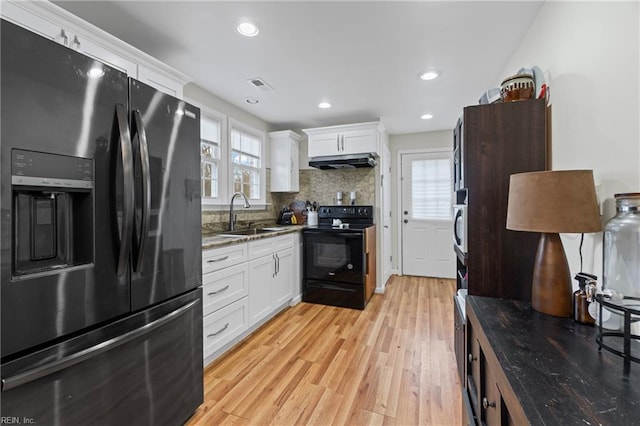 kitchen featuring visible vents, under cabinet range hood, light wood-style floors, black appliances, and a sink