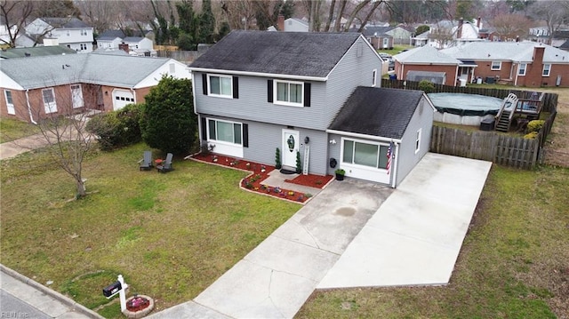 view of front facade featuring fence, a residential view, concrete driveway, a front yard, and a shingled roof