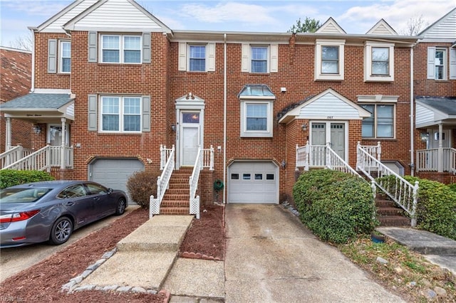 townhome / multi-family property with driveway, brick siding, and an attached garage