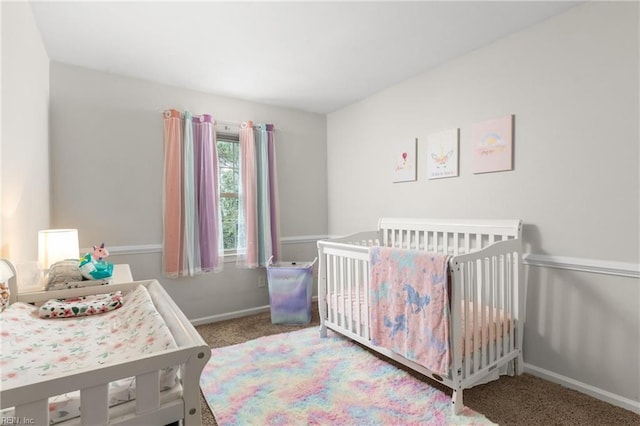 carpeted bedroom featuring a nursery area and baseboards