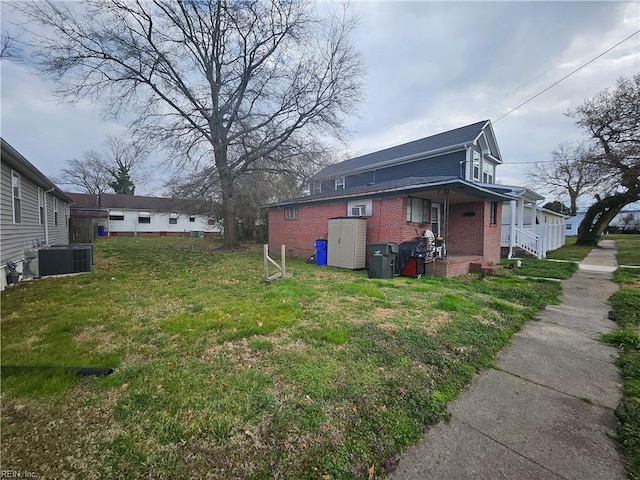 view of side of home featuring central air condition unit, brick siding, and a lawn