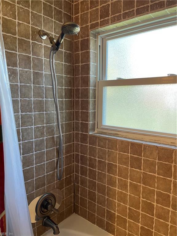 bathroom featuring a wealth of natural light and shower / bathtub combination with curtain