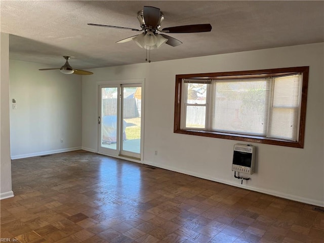 unfurnished room with baseboards, heating unit, a textured ceiling, and ceiling fan