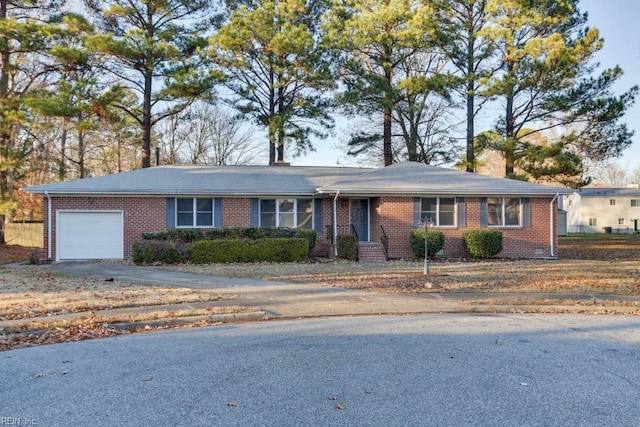 single story home with driveway, brick siding, a chimney, and an attached garage