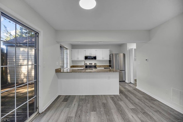 kitchen with visible vents, baseboards, stainless steel appliances, wood finished floors, and white cabinetry