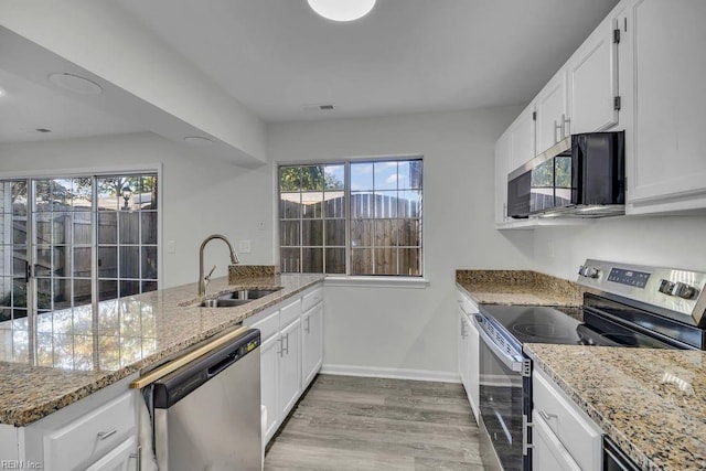 kitchen with a sink, appliances with stainless steel finishes, a peninsula, and white cabinets