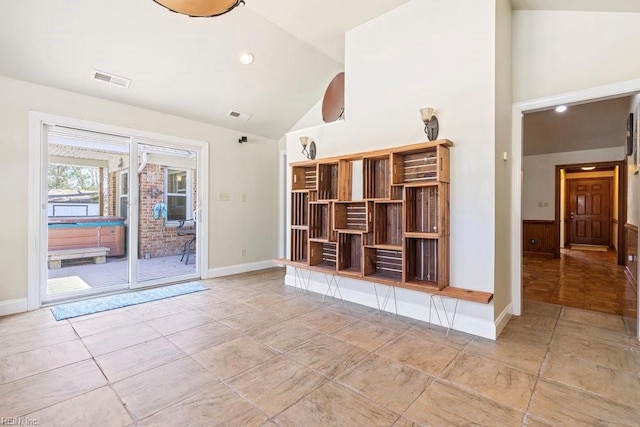 unfurnished living room with baseboards, visible vents, and high vaulted ceiling