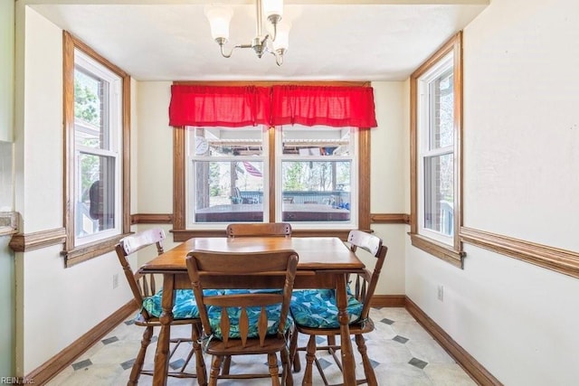 dining area with an inviting chandelier, light floors, and baseboards