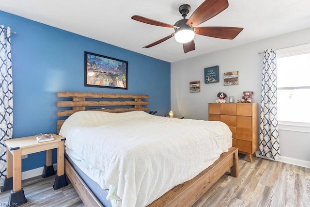 bedroom featuring baseboards, wood finished floors, and a ceiling fan