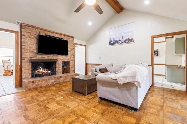 living area with a fireplace, beam ceiling, a ceiling fan, and high vaulted ceiling