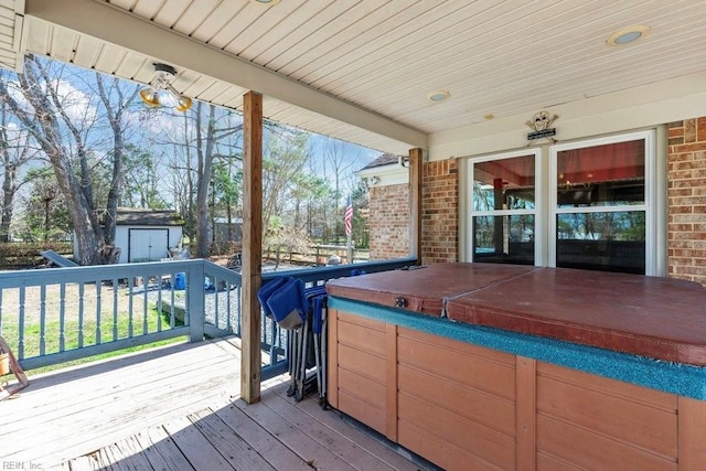 wooden deck with a shed, a hot tub, and an outdoor structure