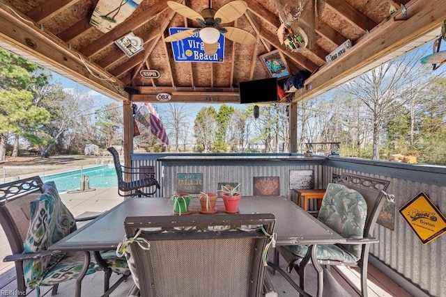 wooden terrace featuring a gazebo, outdoor dining space, an outdoor pool, and a ceiling fan