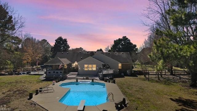 pool featuring a diving board, a yard, a deck, and fence