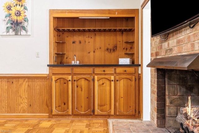 bar with indoor wet bar, wooden walls, and wainscoting