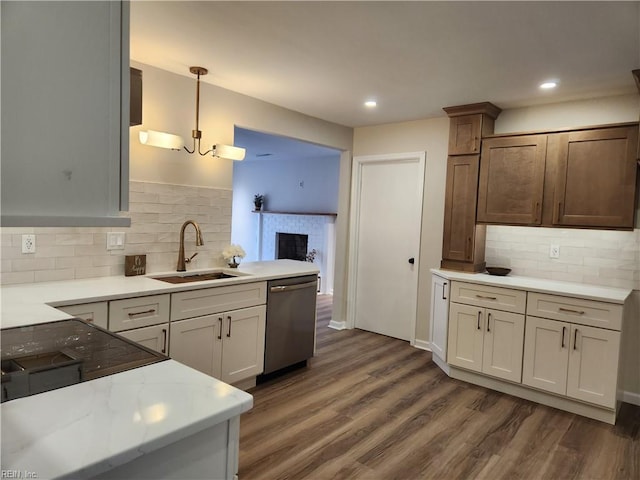 kitchen featuring dark wood-style floors, a sink, dishwasher, a brick fireplace, and decorative light fixtures