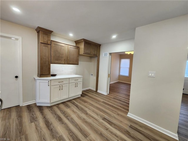 kitchen with decorative backsplash, baseboards, light wood-style floors, and light countertops