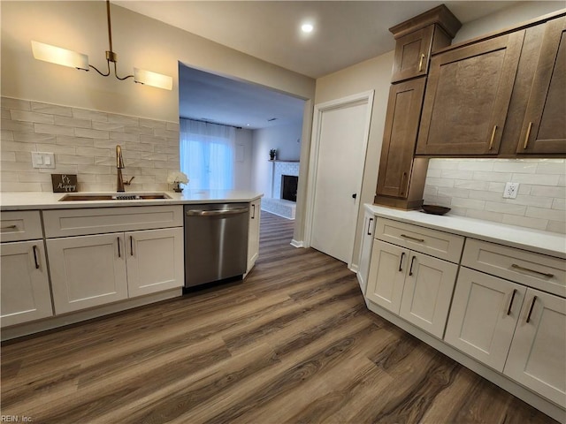 kitchen featuring dark wood finished floors, a fireplace, a sink, light countertops, and dishwasher