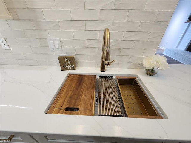 interior details with light stone counters, decorative backsplash, and a sink