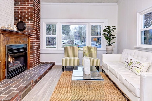 living area featuring a fireplace, crown molding, and wood finished floors